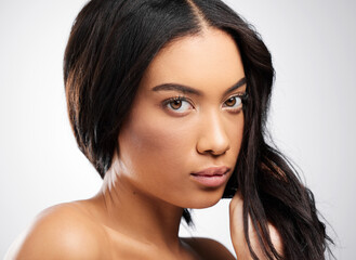 Fototapeta premium Youve gotta take your haircare seriously. Cropped portrait of an attractive young woman posing in studio against a grey background.