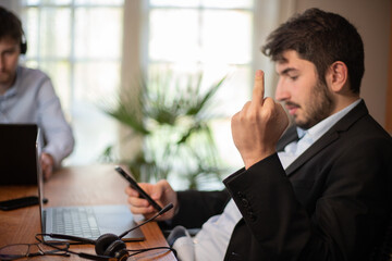 Homme d'affaire ou employé de bureau fatigué et énervé qui montre le doigt du milieu en faisant un doigt d'honneur. Il n'est pas content et il en a marre du travail