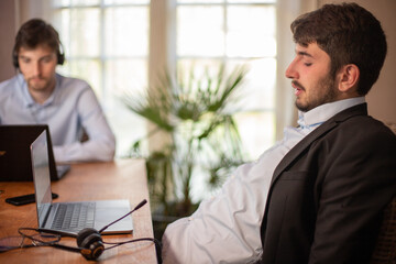 jeune homme d'affaires ou employé de bureau fatigué à la fin de la journée qui se détend sur sa chaise devant son ordinateur. Il en a marre du travail