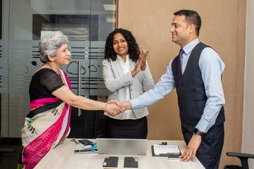 Smiling diverse business partners shaking hands at meeting 