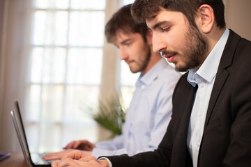 Fototapeta premium deux jeunes employés de bureau ou hommes d'affaires travaillent ensemble avec des ordinateurs portables.