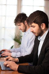 deux jeunes employés de bureau ou hommes d'affaires travaillent ensemble avec des ordinateurs...