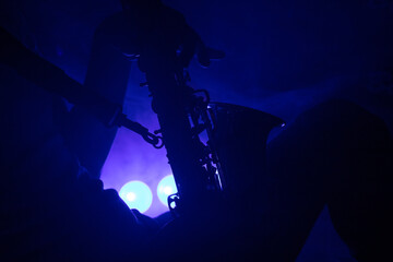 un jeune homme joue du saxophone sur scène dans un club. Il prend du plaisir à jouer. Jazz et blues, dans une ambiance nocturne