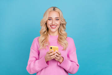Photo of nice millennial wavy blond lady hold telephone wear pink jumper isolated on blue color background