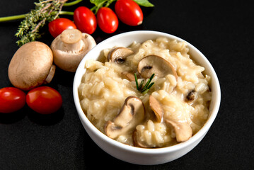 Bowl with mushroom risotto on black background.