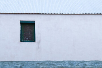Obraz na płótnie Canvas Plastered White Farmhouse Wall With Window And Sheet Roof