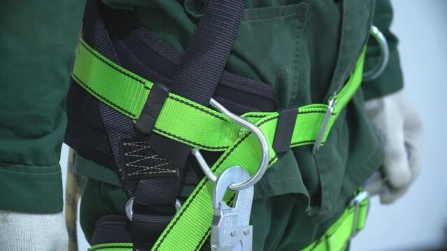 Working at height equipment. Fall arrestor device for worker with hooks for safety body harness on selective focus. Worker as a background.