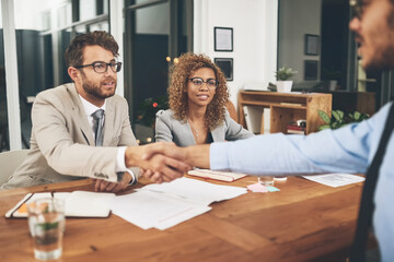 Theyre intrigued by the skills he could offer the company. Shot of businesspeople shaking hands during a job interview in an office.