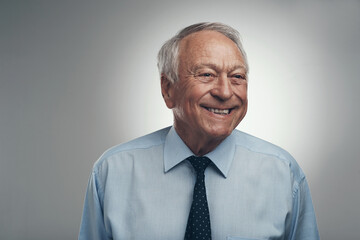 Happiness is never something that goes out of style. Shot of a senior businessman standing alone against a grey background in the studio during the day.