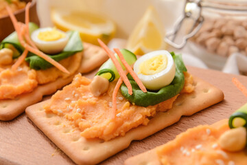 Crispbreads with tasty hummus on wooden board, closeup