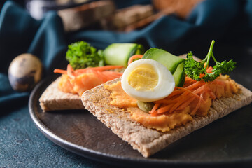 Plate with crispbreads and tasty hummus on dark background, closeup