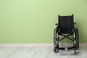 Empty wheelchair near color wall - obrazy, fototapety, plakaty