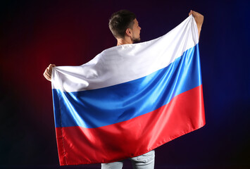 Handsome man with flag of Russia on dark background, back view