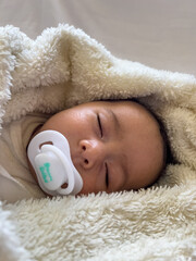 Sweet peaceful baby lying on a white bedsheet enjoy daytime nap