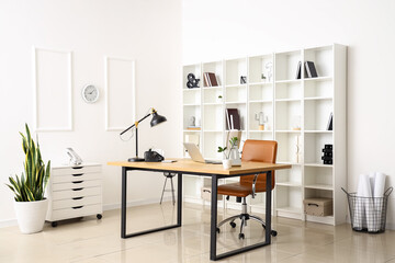 Modern workplace with laptop and lamp in interior of light office