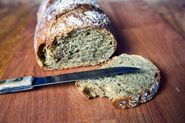 Loaf of bread and knife on wooden table