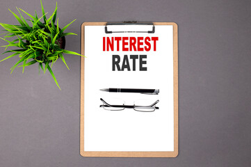 INTEREST RATE on the brown clipboard on the grey background. Business concept