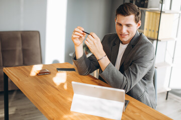 Modern smiling man, office worker working in the office at the computer