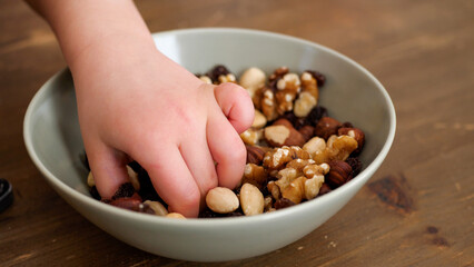 Hands of a kid taking helthy snacks from a bowlPeople taking healthy snacks from a bowl