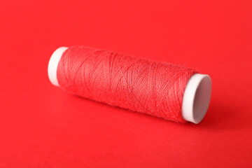 Red sewing thread spool on color background
