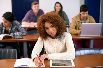 Feeling positive about my career options. Shot of a student daydreaming while working at her desk in class with a digital tablet.