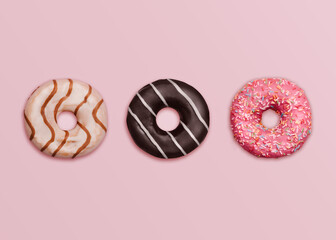 Donuts. Top view photo in minimal style. Assorted glazed doughnuts on pastel pink background