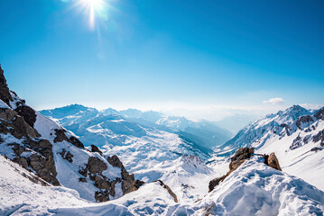Shining sun over snow covered mountain. Beautiful white landscape against blue sky. Alps on sunny day during winter.