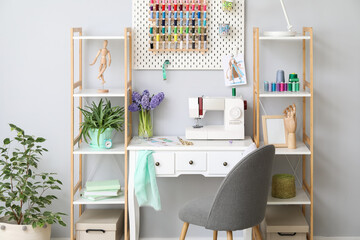 Interior of stylish atelier with tailor's workplace, shelving units and pegboard