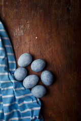 Blue painted easter eggs, some blue striped fabric on brown wooden rustic table background. Copy space, vertical shot, top view