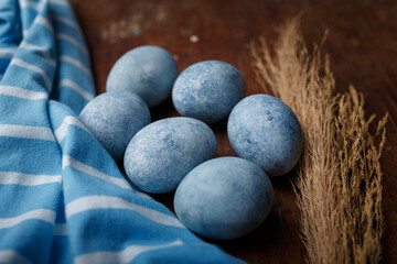Blue painted easter eggs, some blue striped fabric on brown wooden rustic table background. Close up shot
