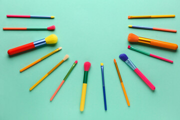 Composition with set of makeup brushes on color background