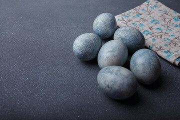 Easter eggs DIY painted blue on grey wooden background with kitchen towel. Copy space