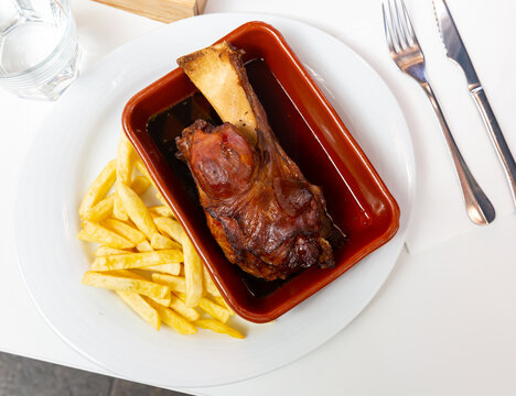 Oven baked pork knuckle with french fries on plate. High quality photo