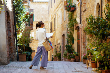 stylish woman with map enjoying promenade in Tuscany, Italy