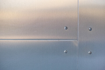 Brushed sheet metal. Shiny sheet metal attached with bolts.