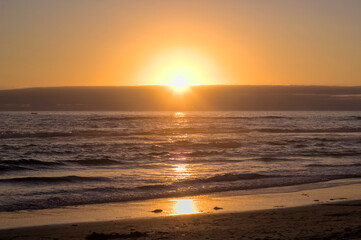 puesta de sol y ocaso en la orilla de playa con nubes en el horizonte y un pequeño bote