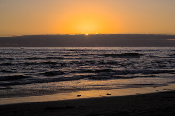 puesta de sol y ocaso en la orilla de playa con nubes en el horizonte y un peque&ntilde;o bote