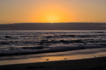 puesta de sol y ocaso en la orilla de playa con nubes en el horizonte y un pequeño bote