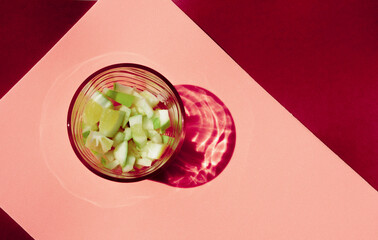 Top view of lime summer drink on pink background. Sunny day fresh cocktail caipirinha garnished with apple slices.
