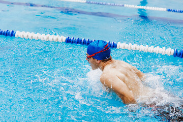 hispanic young man swimmer athlete wearing cap and goggles in a swimming training at the Pool in Mexico Latin America	