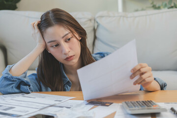 Financial owe asian woman, female hand in cover face, sitting in stressed and confused by calculate expense from invoice or bill, have no money to pay, mortgage or loan. Debt, bankruptcy or bankrupt.