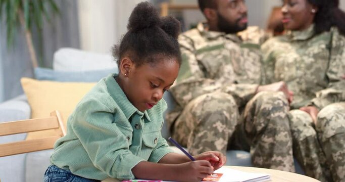 Child drawing alone while military parents relaxing on sofa