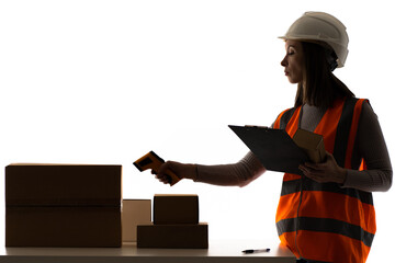 Data collection terminal in hands of girl. Warehouse worker uses data collection terminal. Work as warehouse employee. Woman in orange vest next to cardboard boxes. Concept she scans barcode on box
