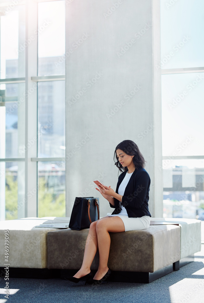 Poster taking time to reply to her clients. full length shot of an attractive young businesswoman using a s