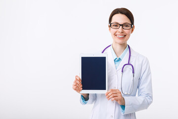 Cheerful young female doctor holding a clipboard in her hand and pointing to copyspace with a gesture