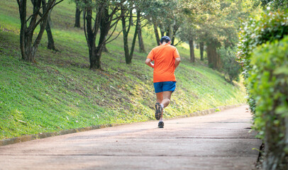 Back view of man runner jogging on an outdoor path during sunset. Healthy lifestyle concept.