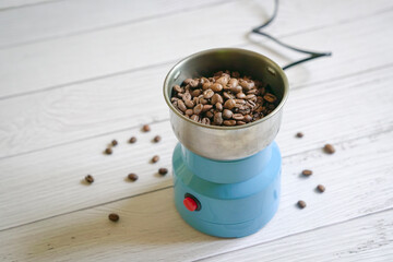 Plakat Coffee beans inside a grinder. On white tabletop with copy space.