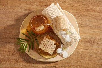 Closeup view of honey and honey comb in spa decorated with towel in wood background