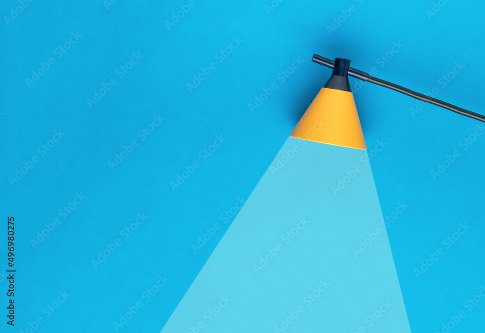 Wall mural yellow lamp with a beam of light on a blue background. minimal business concept.