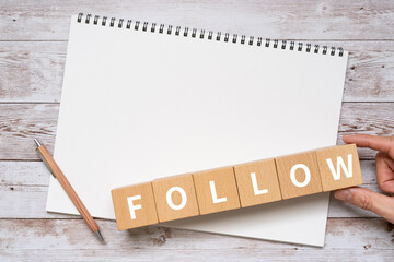 フォローのイメージ｜「FOLLOW」と書かれた積み木、ノート、ペン、手